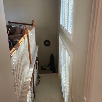 Stairwell with white trim, plantation shutters and tall windows
