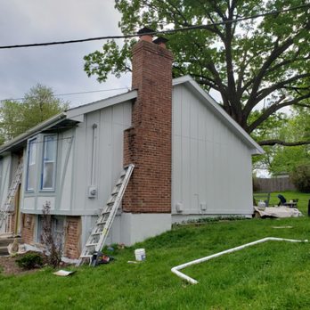 Exterior siding and brick chimney prepped with ladders in place