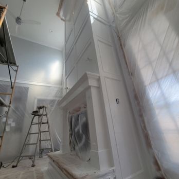 Floor-to-ceiling white fireplace millwork being finished